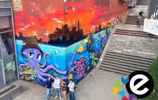 An der Wand der Turnhalle ist bis zu vier Meter hoch ein Graffiti mit Krake, Fischen und einem Graffiti "Stadtteilschule" zu sehen.
