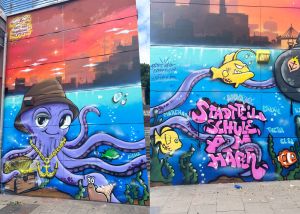 Die lila Graffiti-Krake hat einen Sonnenhut auf sowie eine goldene Kette mit Anker um den Hals und bewcht eine Truhe mit Goldschatz. Ihre langen Arme wandern über den Rest des Bildes.